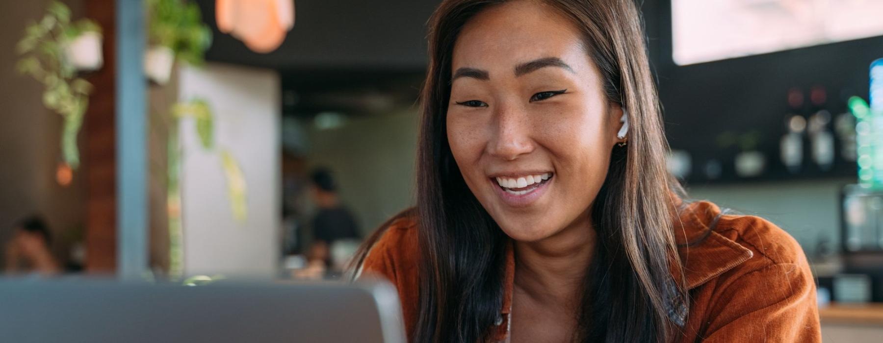 a woman smiling while working on laptop